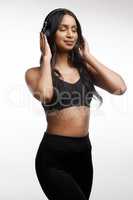 Now Im in the right mindset. Studio shot of a sporty young woman listening to music against a white background.