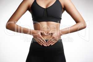 Put in the work to keep your body in shape. Studio shot of an unrecognisable woman making a heart shape with her hands on her stomach against a white background.