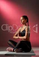 Focus on you completely for a change. Studio shot of a sporty young woman meditating against a red background.