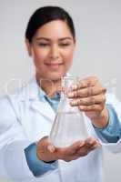 Let me show you my findings. an attractive young female scientist examining a beaker filled with liquid in studio against a grey background.