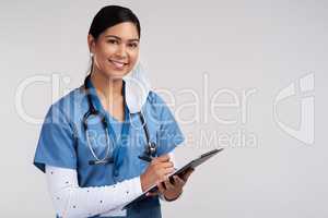 When the doctor is cute, forget the fruit. Portrait of a young doctor wearing a stethoscope and making notes on a clipboard against a white background.