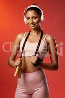 Fitness has become my favourite habit. Studio portrait of a sporty young woman posing with a skipping rope around her neck against a red background.