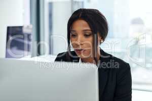 Steady focus gets you further. a young businesswoman using a computer in a modern office.