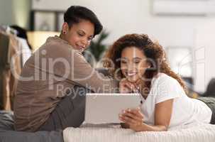 I want to hold your hand at 80. a young lesbian couple using a tablet while relaxing in their bedroom.