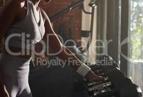 Levelling up with some heavy weights. Closeup shot of an unrecognisable woman taking a dumbbell from a rack in a gym.