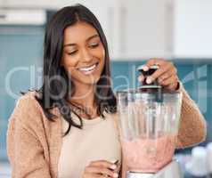 Smoothies are loaded with all the good stuff. a young woman preparing a healthy smoothie at home.