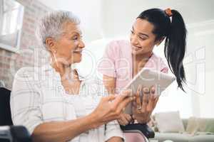 Patience is timeless. a young nurse sharing information from her digital tablet with an older woman in a wheelchair.