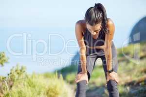 Its a challenge, but youll survive it. a sporty young woman catching her breath while exercising outdoors.