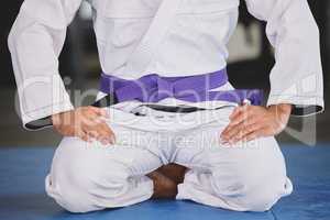 Showing respect to the sport. an unrecognizable young man kneeling in full jiu jitsu gi in the gym.