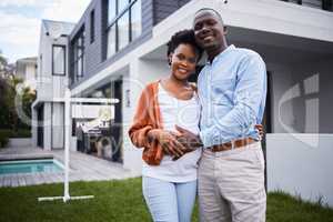 Our lives are changing in many ways. Portrait of a young couple standing outside their new home.