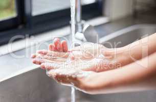 Hygiene is a priority to me. an unrecognizable woman washing her hands in the sink at home.