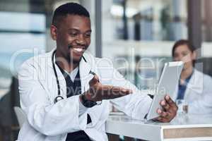 Ive been meaning to call you. a young male doctor taking a break and using his digital tablet.