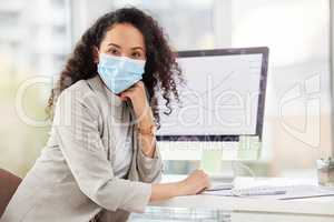 The economy isnt the same as before. Portrait of a young businesswoman wearing a face mask while working on a computer in an office.