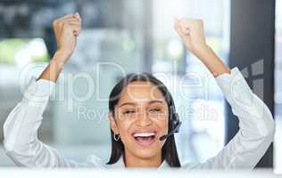 Silent celebration for the client who figured it out. a young call centre agent sitting in the office and wearing a headset while celebrating an achievement.