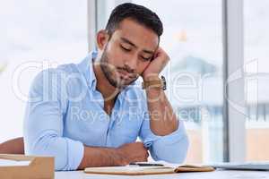 Feeling like I need to rest my eyes. a young businessman looking bored in his office.