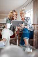 Will you send me that image. two female friends drinking coffee while using a digital tablet.