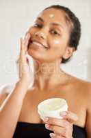 Its a noticeable glow. young woman using with facial moisturiser at home.