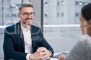 Smiling makes everyone more comfortable. two businesspeople talking in an office.