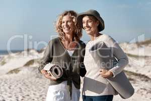 Where should we set up. two attractive mature woman standing with their on the beach.