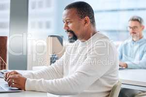 Finishing up tasks with speed. a mature businessman working on a laptop in an office.