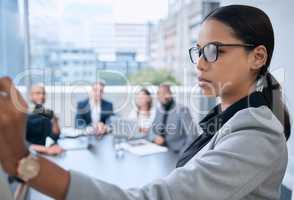 Giving her team a quick briefing on new policies. a young businesswoman using a whiteboard during a presentation in an office.