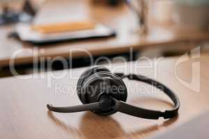 Someone will be by shortly to help you. Still life shot of a wireless headset on a desk in a call center.