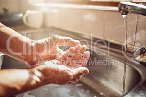 Wash it good before you touch the food. an unrecognisable man washing his hands in the kitchen sink at home.