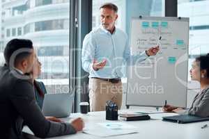 Following through on their big plans. a mature businessman giving a presentation to his colleagues in an office.