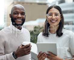 Staying on trend means staying updated. Portrait of two businesspeople drinking coffee and using a digital tablet outside an office.