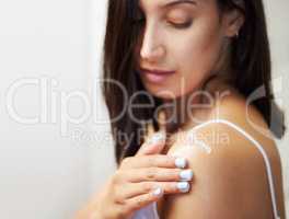 It leaves my skin feeling soft and smelling amazing. a beautiful young woman applying moisturiser to her skin.