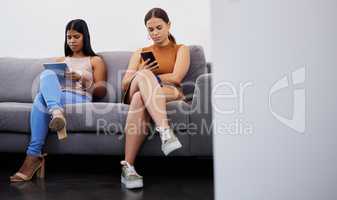 One step closer to our dream career. two young women using their devices while waiting to be interviewed in a modern office.