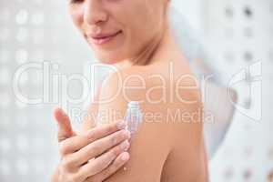 Daily exfoliation is the key to smooth skin. a woman applying moisturiser to her arms and shoulders.