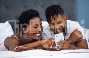 With a strong connection comes a strong marriage. a young couple using a smartphone in bed at home.