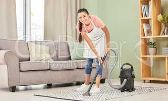 I dont mind vacuuming. a young woman vacuuming a carpet at home.