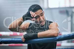 Fit, active or healthy boxing man feeling tired, hot and wiping sweat after workout, training or exercise in ring. Sporty, athletic or strong boxer upset after losing kickboxing fight or sports match