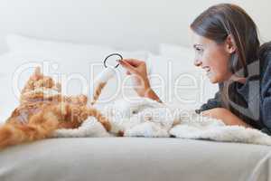 Regular play with your furry feline is so important. a young woman playing with her cat at home.