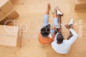 Focusing on our future. a young couple sitting on the floor while looking at an ultrasound picture at home.