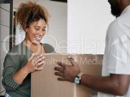 The excitement builds. a young woman receiving a box from a deliveryman at home.