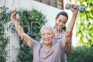 Early bird catches the worm. an older woman lifting dumbbells during a session with a physiotherapist.