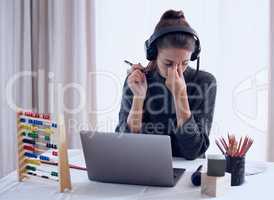Burnout can be prevented with proper self-care. a young getting a headache while teaching an online lesson with her laptop at home.