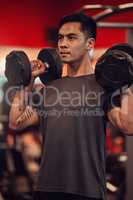 No excuses get that workout in. a young man lifting weights at the gym.
