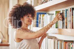 Favour the bold. an attractive young woman browsing a book shelf at home.