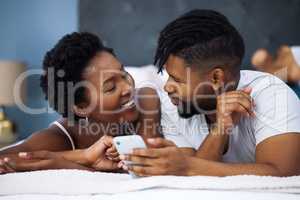 You cant fake this kind of connection. a young couple using a smartphone in bed at home.