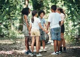 An awesome camp for awesome kids. a group of teenagers standing in a circle and holding hands in nature at summer camp.