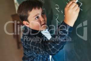 Math is my strongest subject. a young boy standing alone and writing on the blackboard during a lesson in his classroom at school.