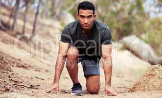The only thing Ill settle for is winning. Portrait of a sporty young man in starting position while exercising outdoors.