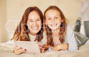 Nothing beats mother and daughter time. an attractive young mother lying on the bed at home and bonding with her daughter while using a digital tablet.