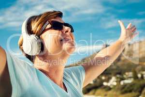 Music is truly the best mood enhancer. a woman wearing headphones while standing outdoors.