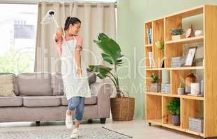 Some random fun while doing chores. a young woman dancing with a mop while doing chores at home.