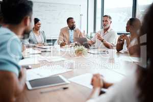 Making some changes would serve us well. a group of staff listening to their boss during a business meeting.